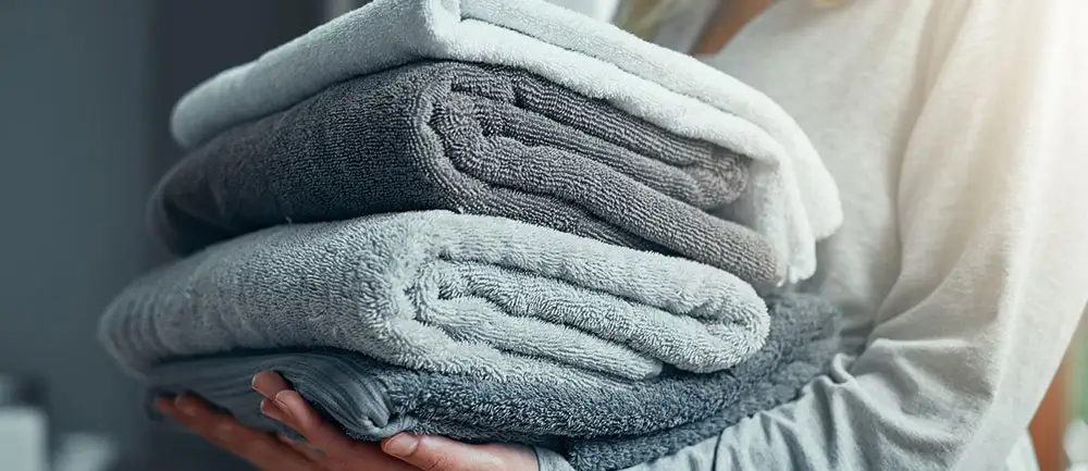 A person carrying a stack of soft towels from washing in softened water