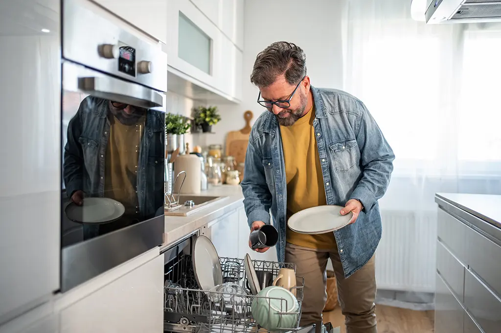 middle-aged-man-emptying-dishwasher