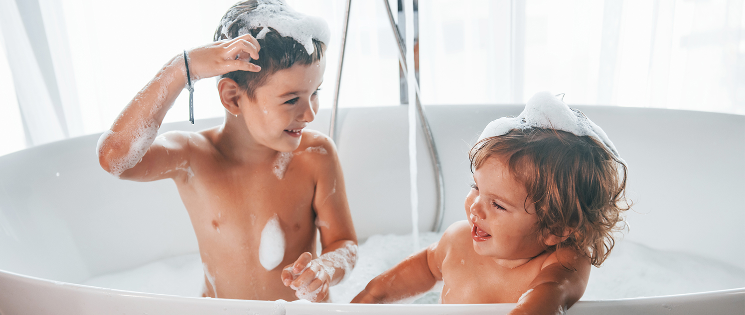 siblings in bath with bubbles